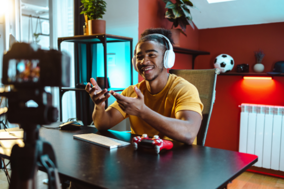 Jovem sorrindo enquanto grava vídeo com controle de jogo.